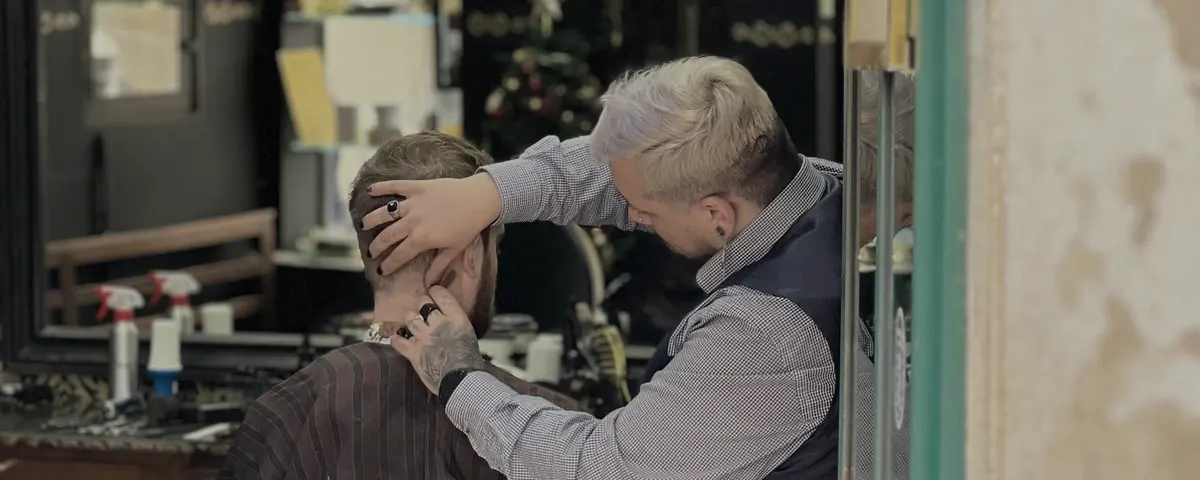 Een kapper knipt het haar van een klant in een klassieke kapperszaak.