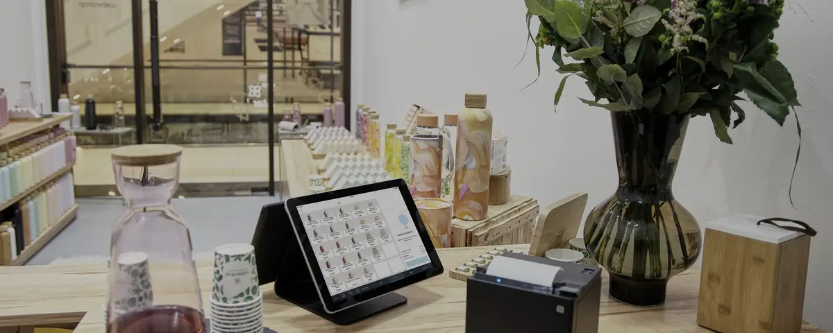 De toonbank van een salon met een kassascherm, een bonnenprinter en een boeket.