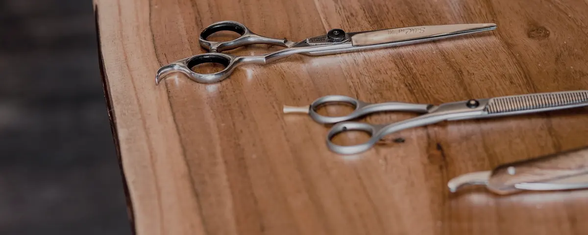 Kappersscharen en een kam naast elkaar op een houten toonbank.